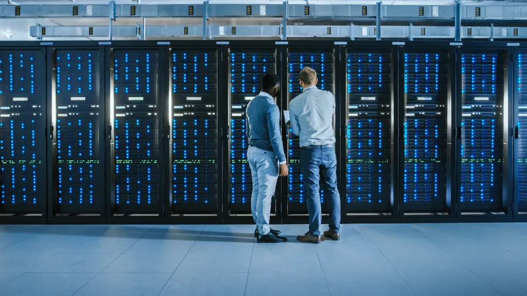 two people invesitgate a stack of servers