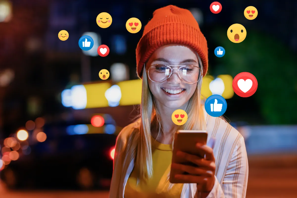 a woman smiles at her phone and social media icons hover over her phone