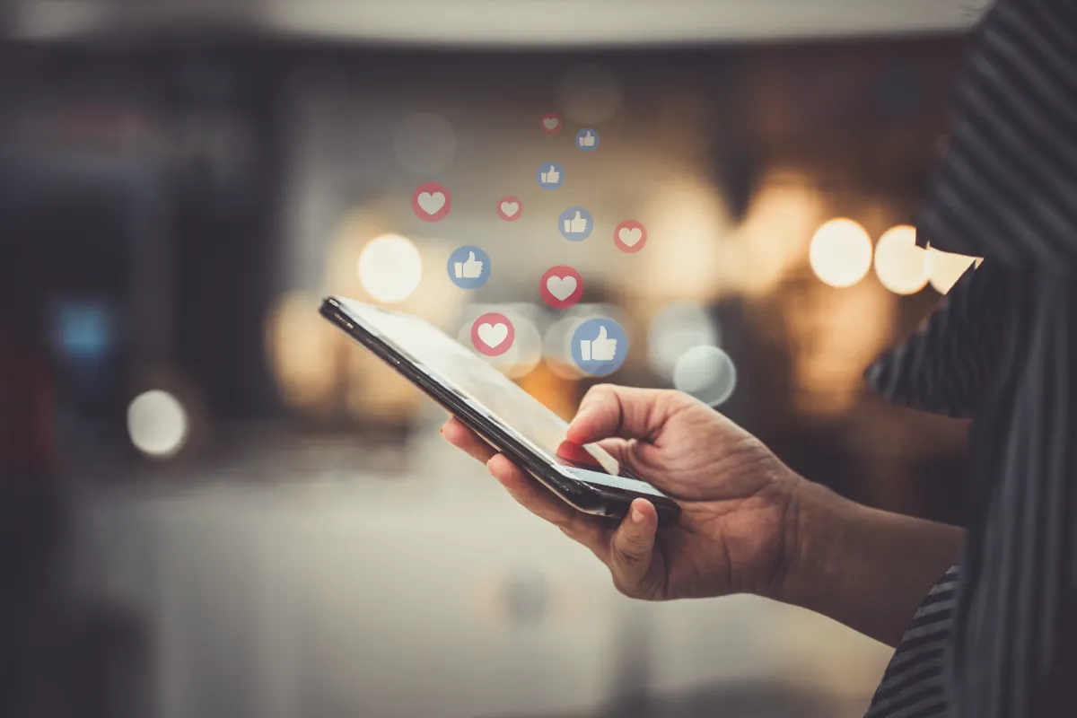 stylized image of like symbols floating over phone in use